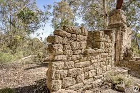 Old stone wall with trees in the background.