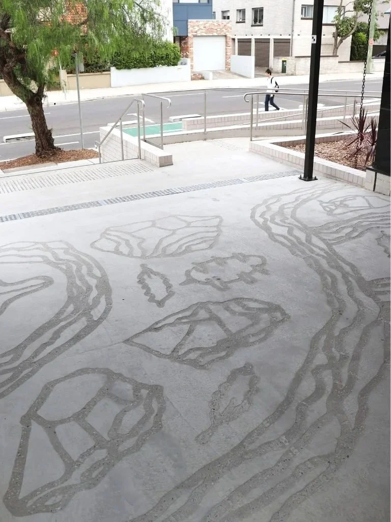 Concrete floor with abstract etched patterns resembling wildlife footprints or shapes.
