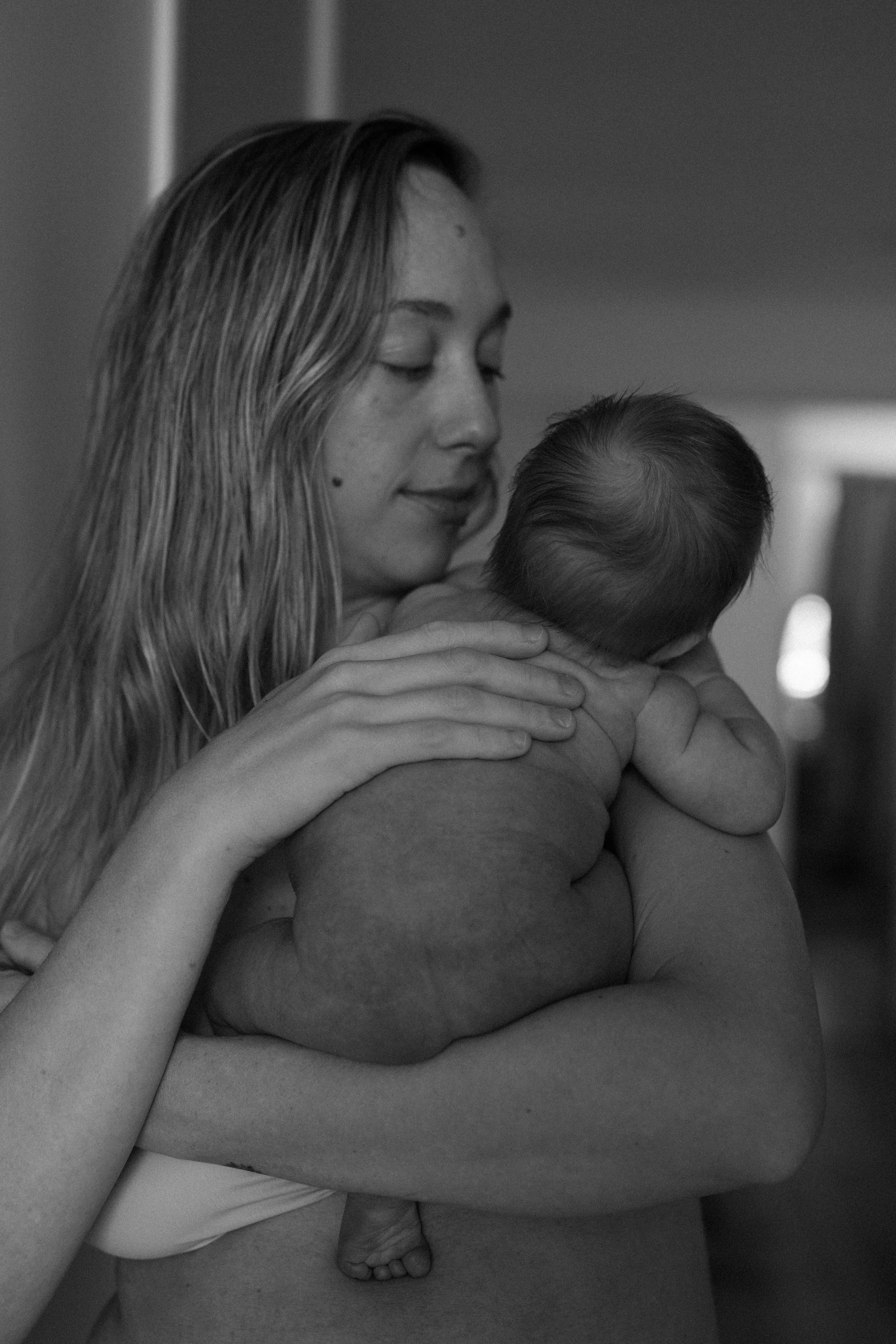A woman gently holding a newborn baby close to her chest.