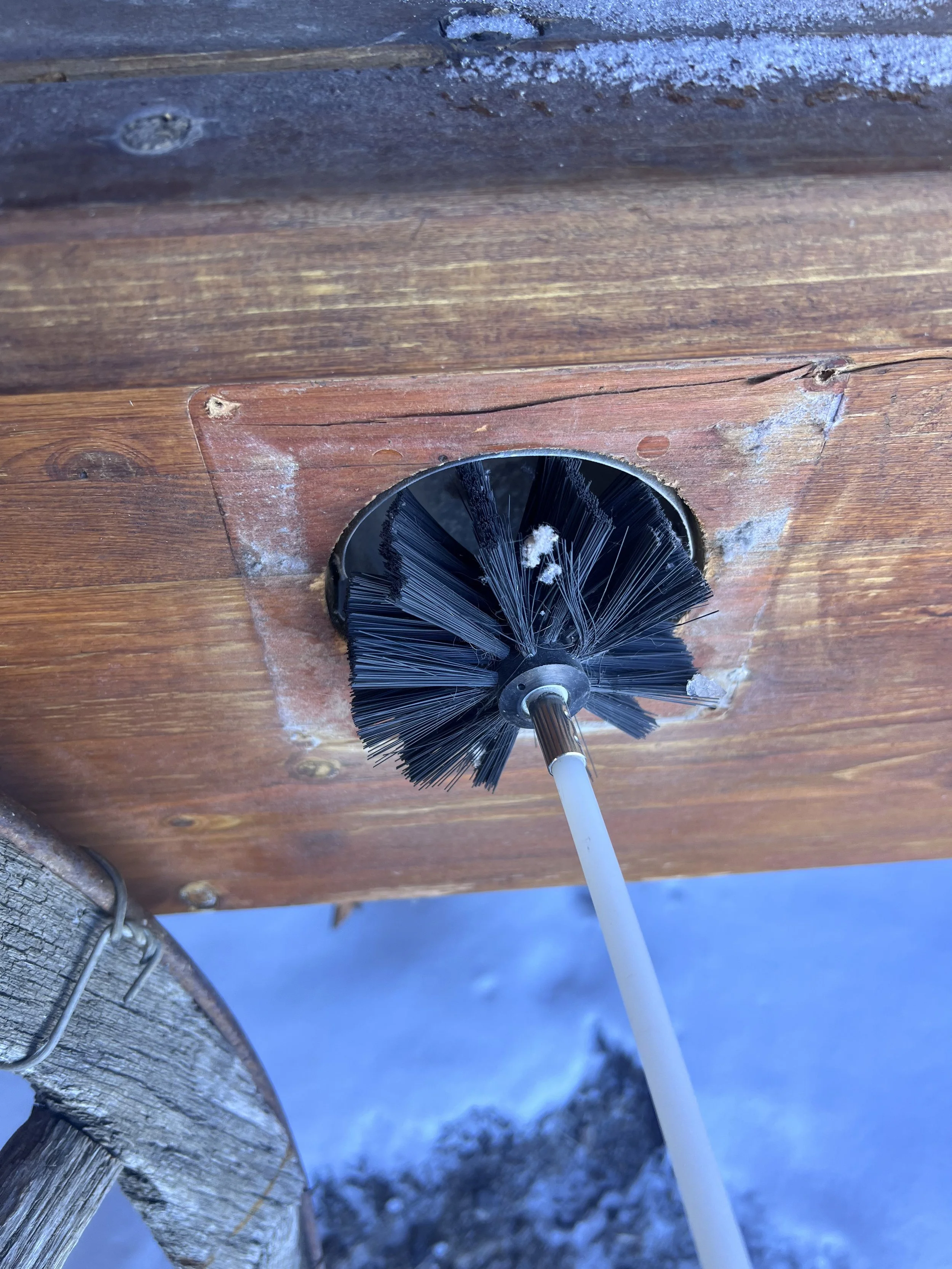 A close-up view of a black brush on a wooden surface with some snow or frost on it.