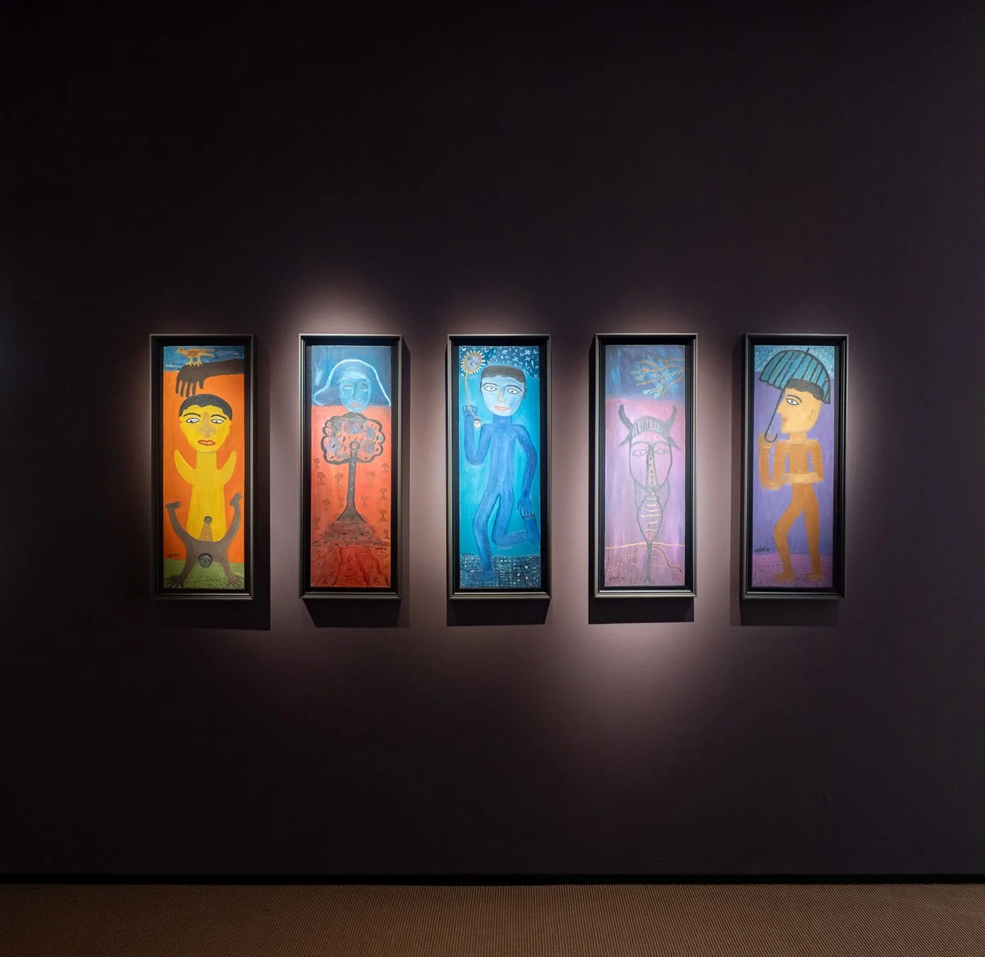 Five framed Indian modernist figurative paintings displayed under dramatic lighting on dark purple walls within a Frieze Masters art fair booth.