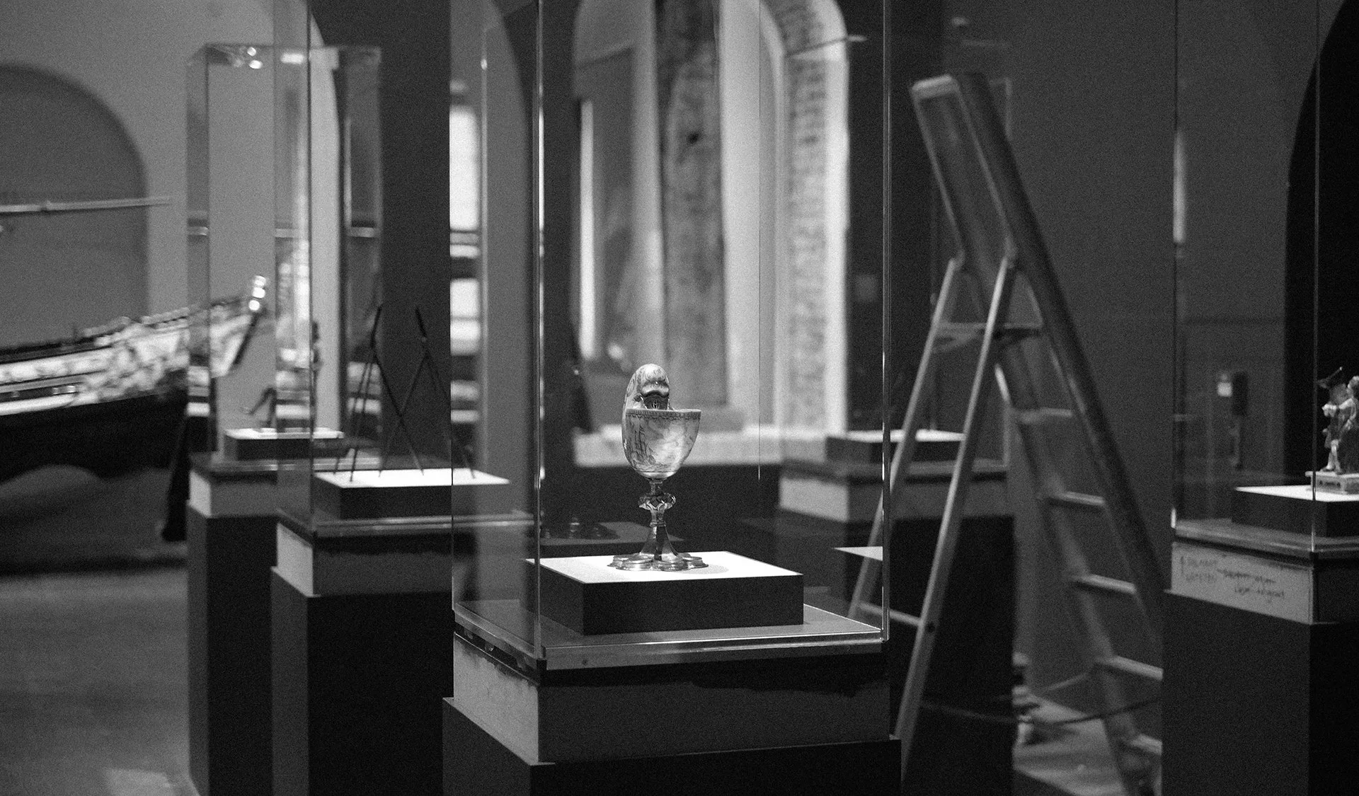 Museum exhibition display case featuring sculptural and archival objects.