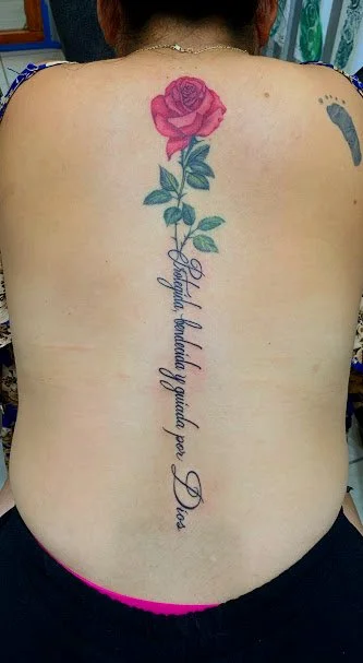 Back tattoo featuring a pink rose with green leaves and a quote in cursive reading, 'Beautiful behind a woman for Duci'.
tatuajes y pircin tatuaje de rosa para mujeres en cabo san lucas
