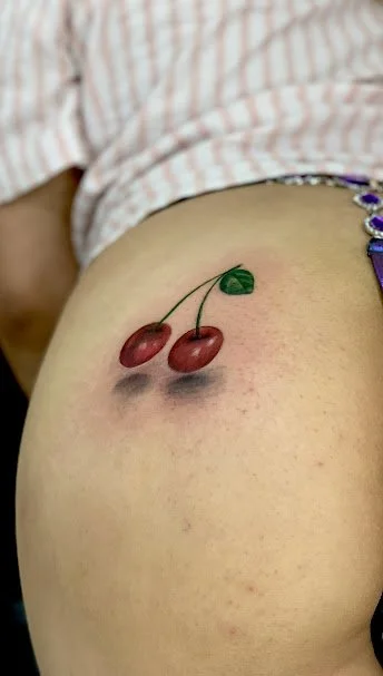 A person with a cherry tattoo on their skin.