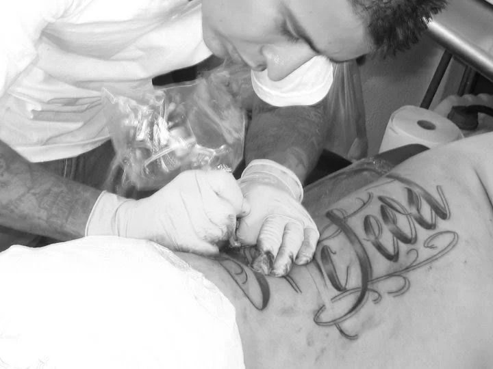 Tattoo artist malaki kidd working on a large, ornate tattoo on a person's back in a tattoo studio in baja tattoo in cabo