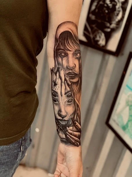 Detailed black and gray portrait tattoo of multiple female faces on a person's forearm, with some faces showing expressions and others partially obscured.
