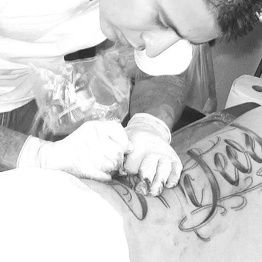 tattoo artist in cabo san lucas, malaki damian kidd tattooing cursive letters on ribs at baja tattoo in los cabos mexico cruise ship dock walk ins