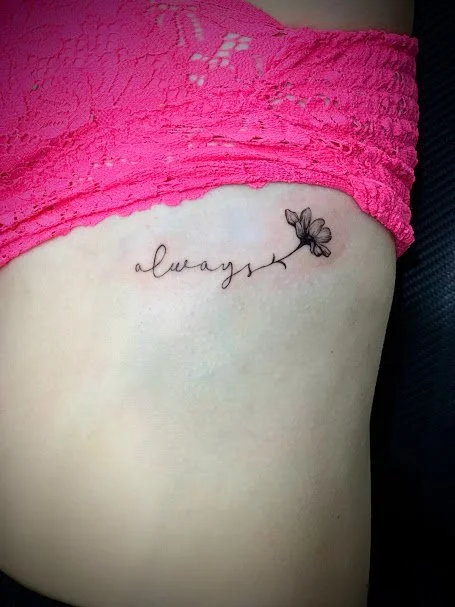 Tattoo of the word 'always' with a butterfly on the side, located on the person's side near the waist.