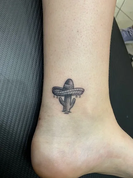 Tattoo of a cactus wearing a sombrero on ankle.