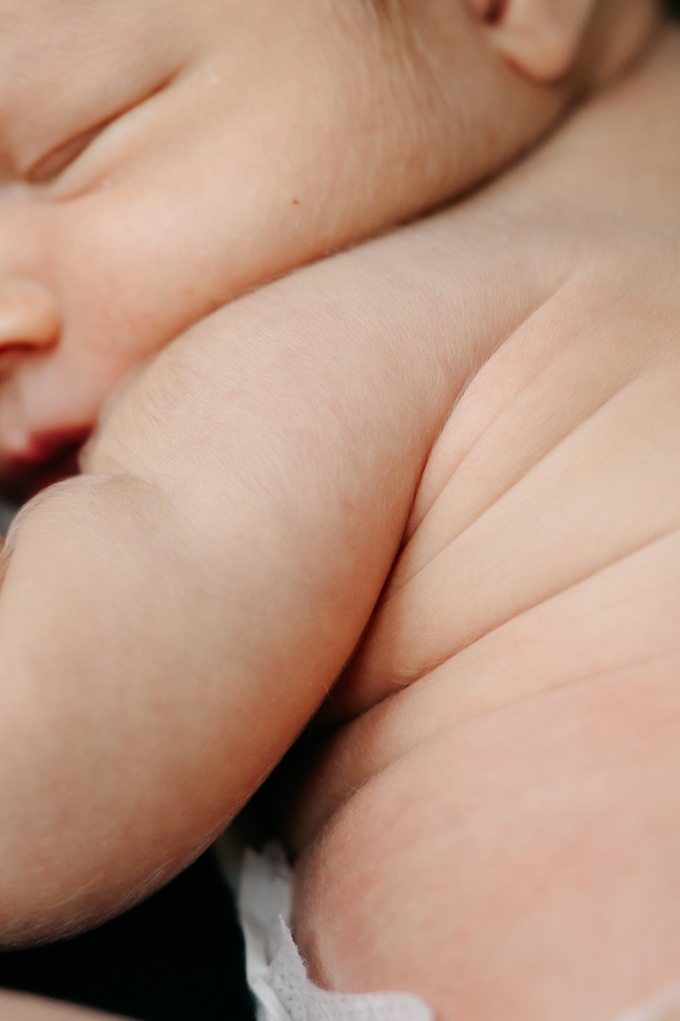 Nærbillede af nyfødt babys bløde hud og små folder på armen.