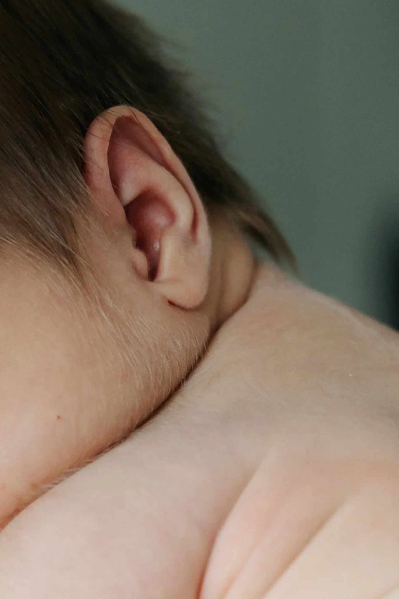 Nærbillede af nyfødt babys øre, nakke og bløde hud.