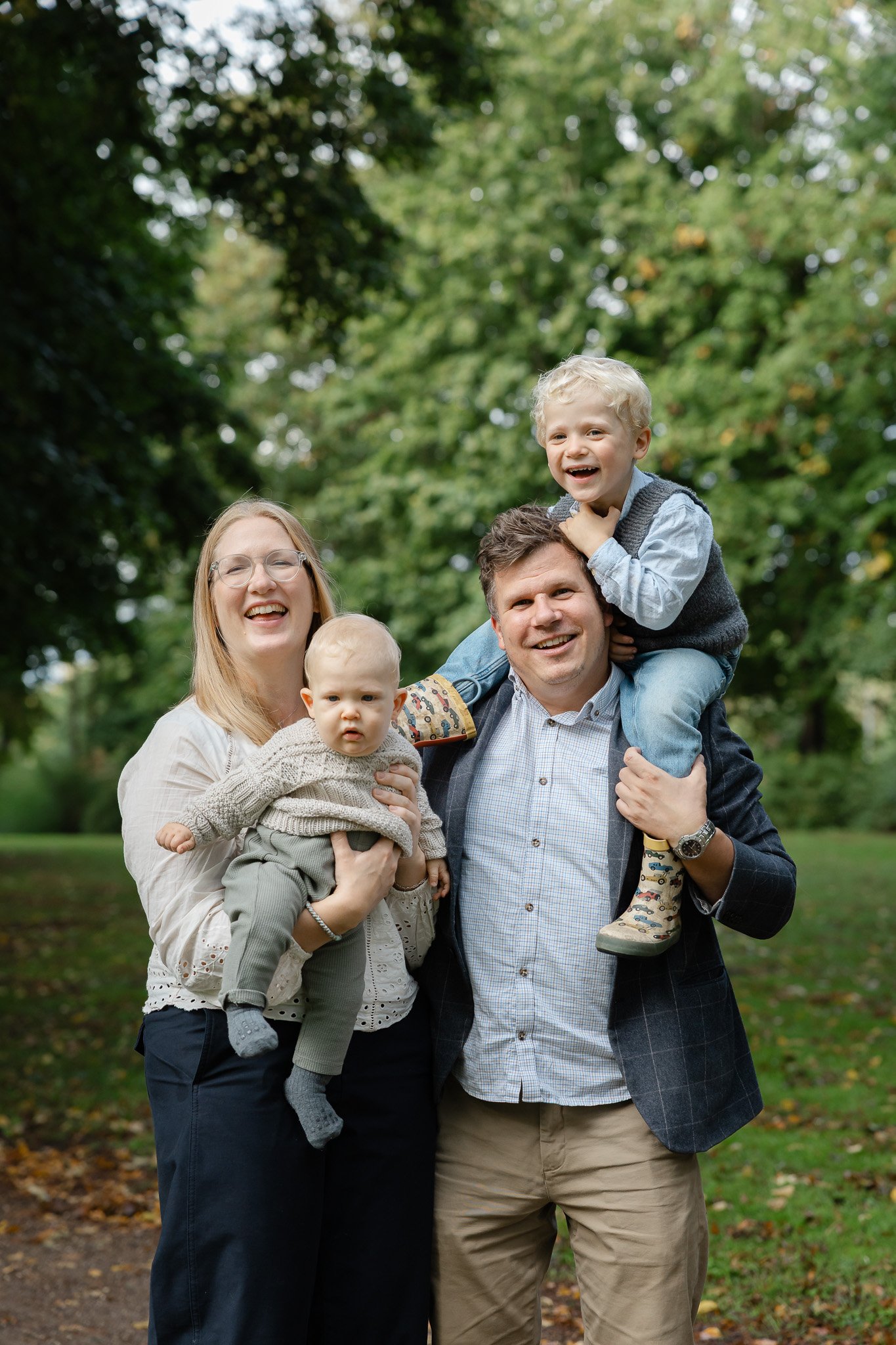 Familie med to børn samlet til et naturligt familiefoto i grønne omgivelser.