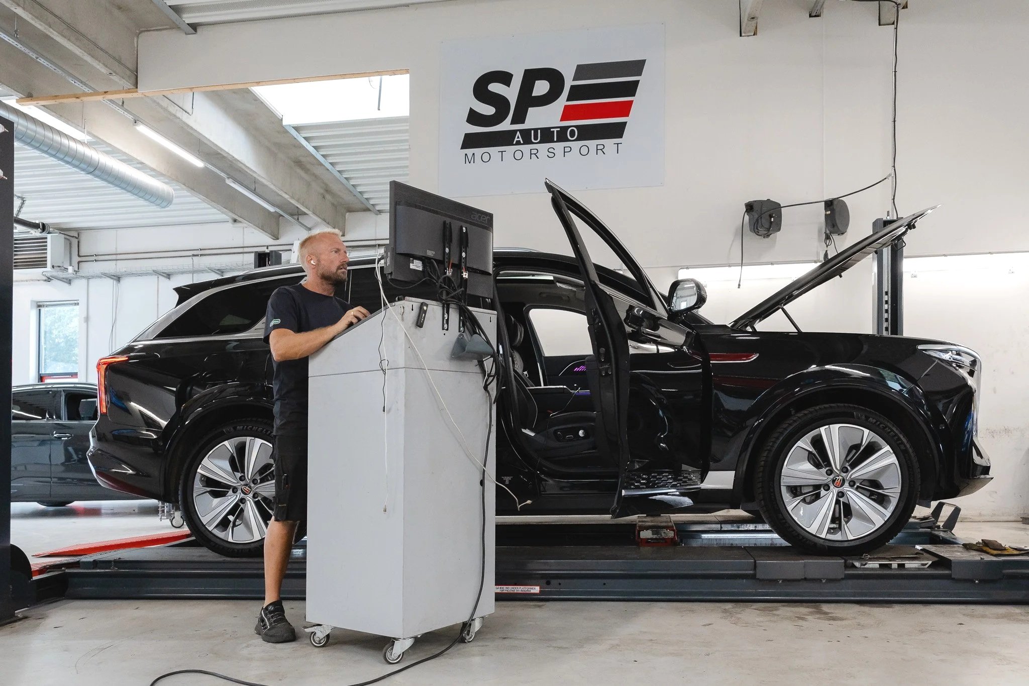 Erhvervsfotografering hos SP Auto med mekaniker, der arbejder på en bil på værkstedet.