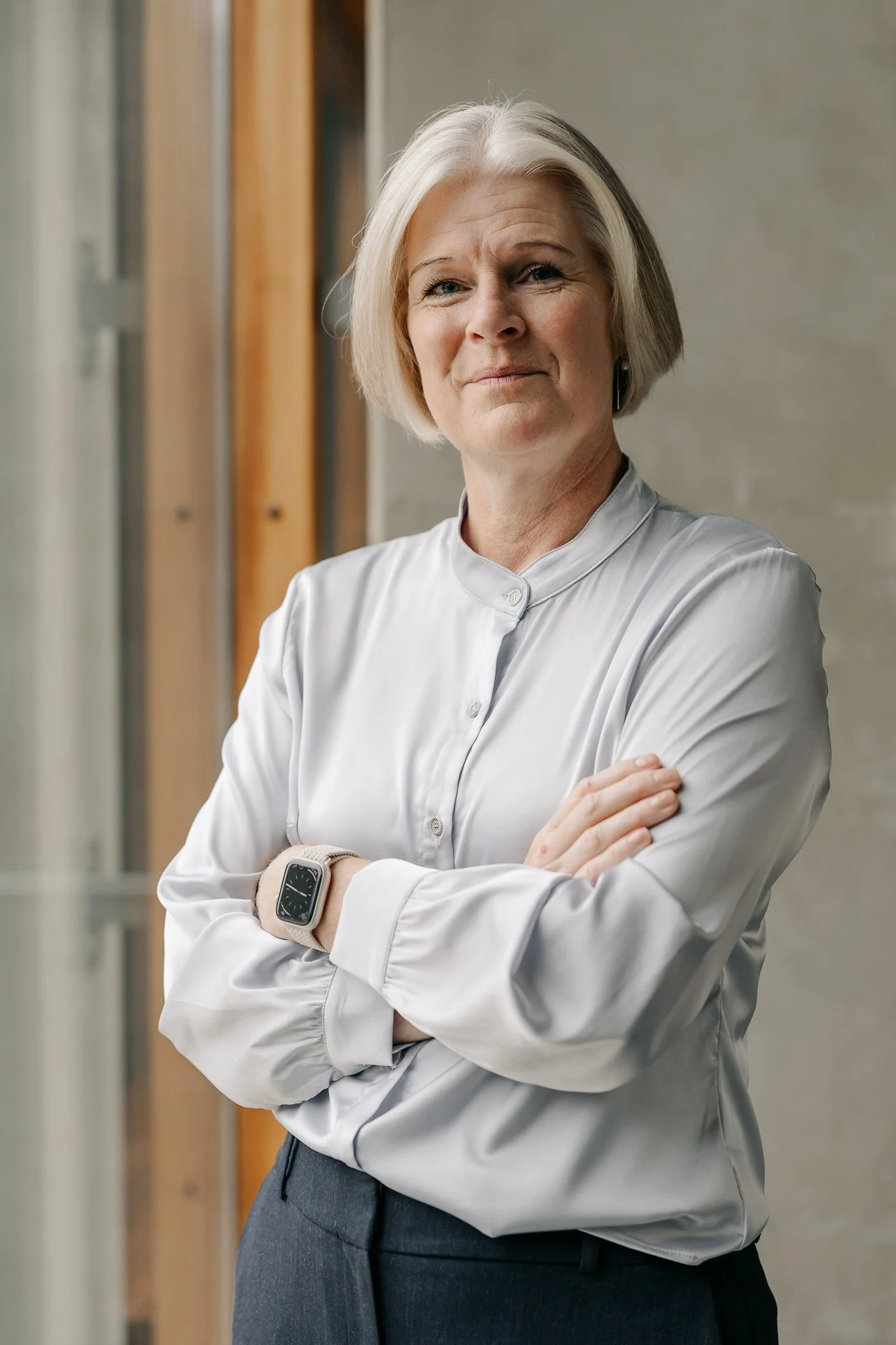 Professionelt erhvervsportræt af en kvinde med armene over kors i lyse omgivelser til hjemmeside og branding.