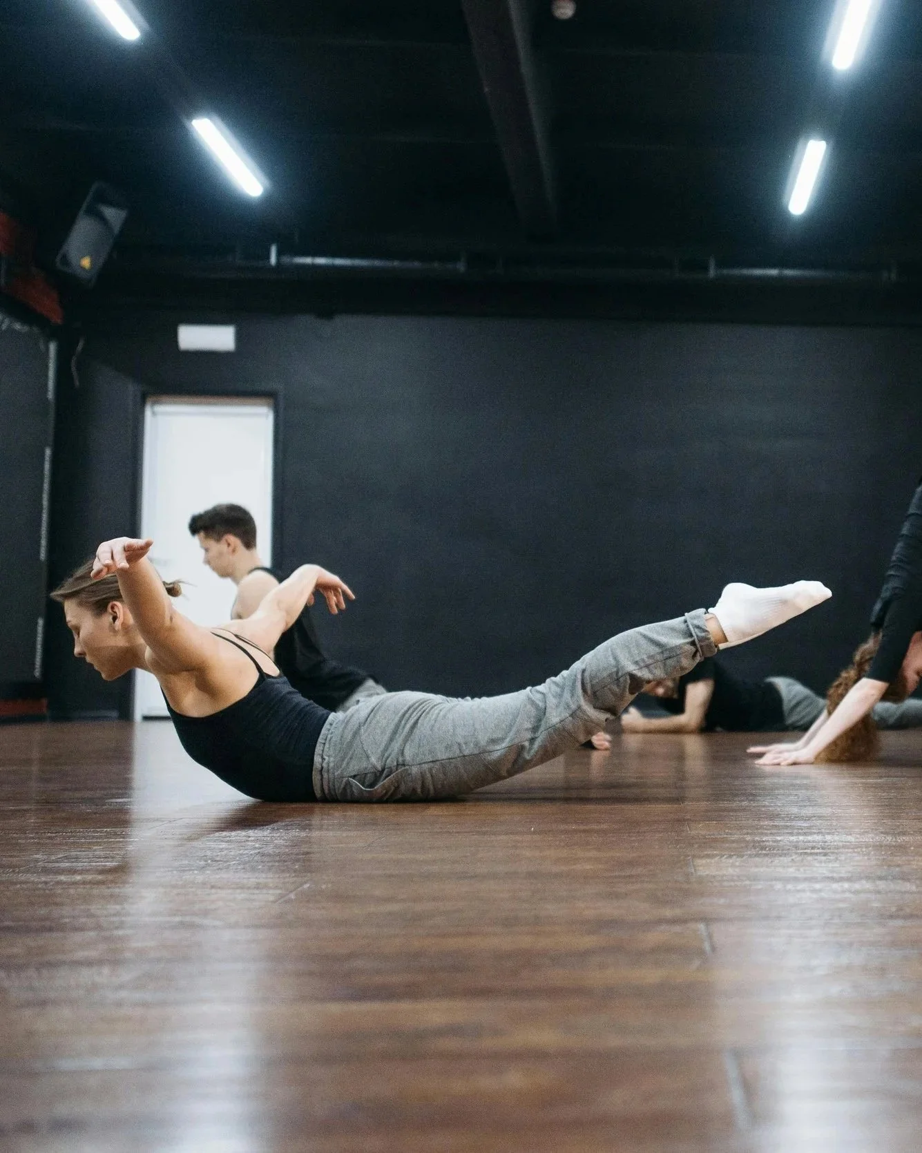 Menschen üben Yoga in einem dunklen Raum auf Holzboden.