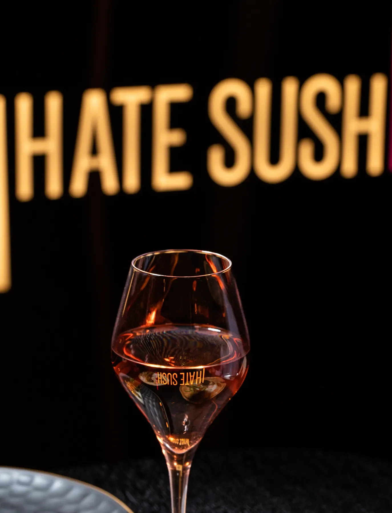 Rožinio šampano taurė su „I HATE SUSHI“ atspindžiu