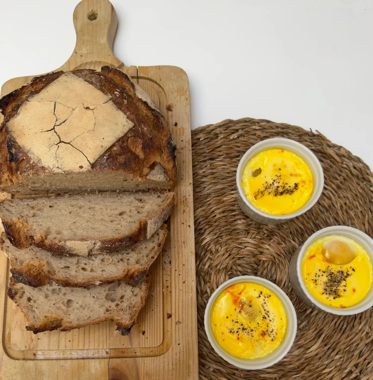 Crèmes au safran en ramequins, servies avec du pain de campagne sur une planche