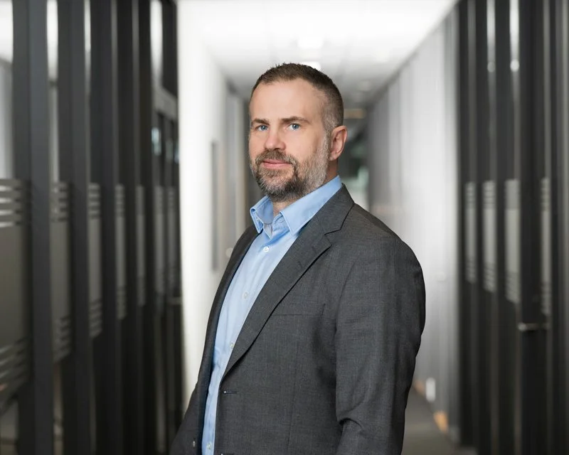 En mann med dress står i en korridor med servere