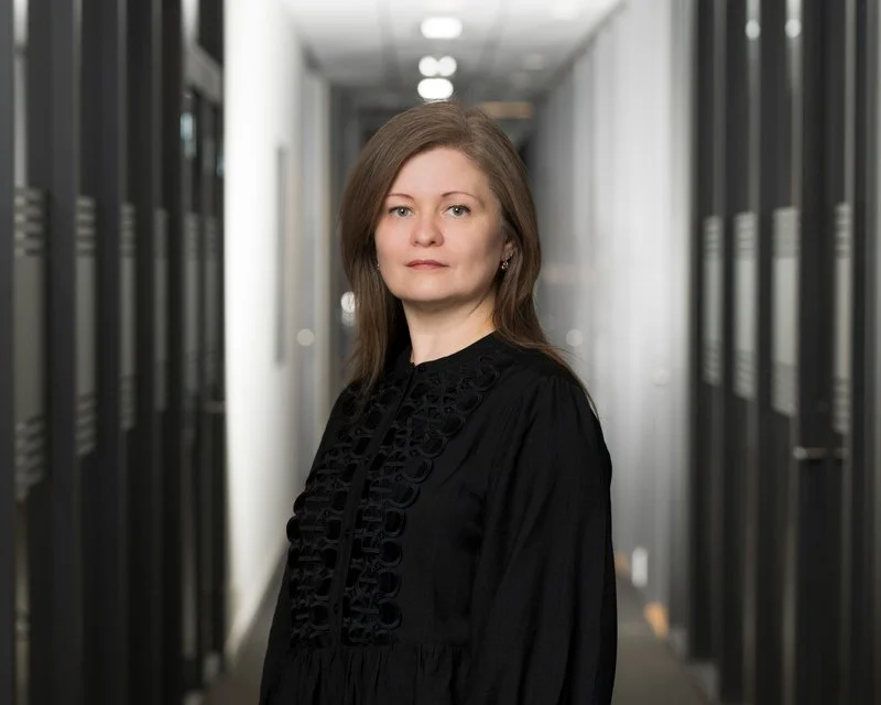 En kvinne i svart kjole står i et serverrom.