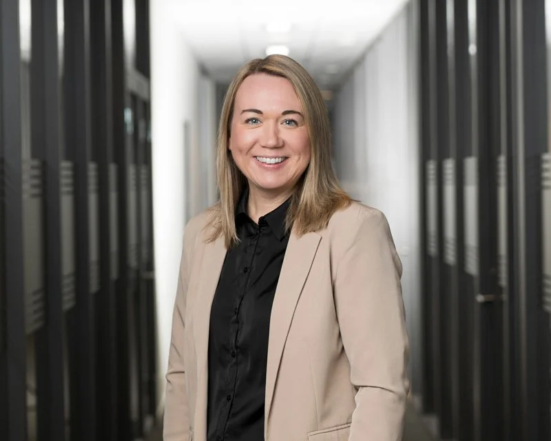 Kvinne smilende i kontorbygning med dataservere