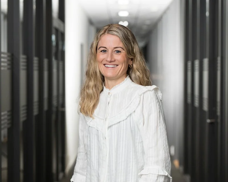 Kvinne smilende i datasenter med servere