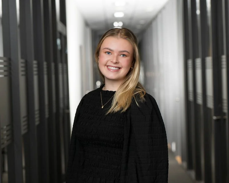 Smilende kvinne med blond hår i et kontorlandskap