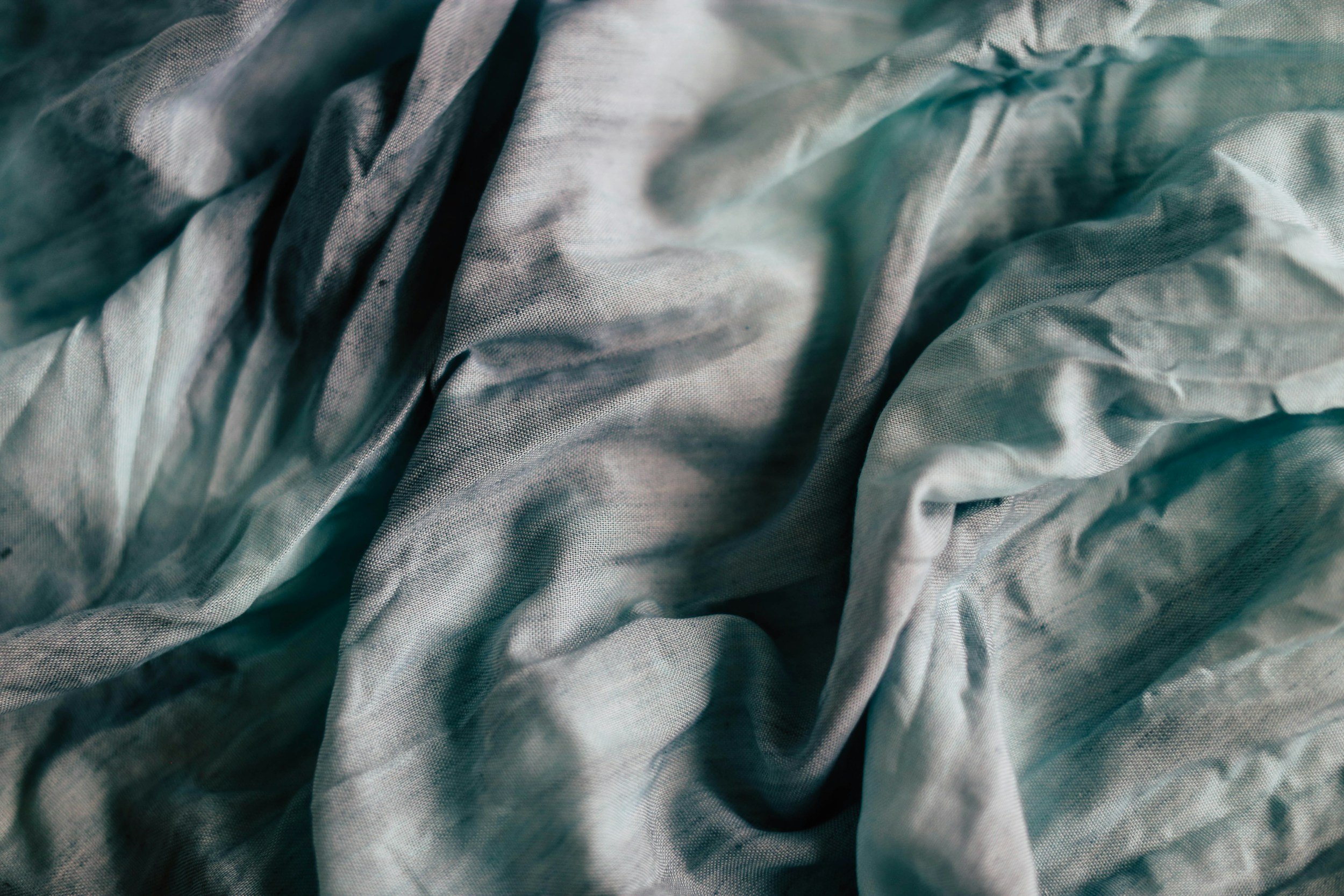 Close-up of crumpled, textured fabric in shades of light blue and gray.