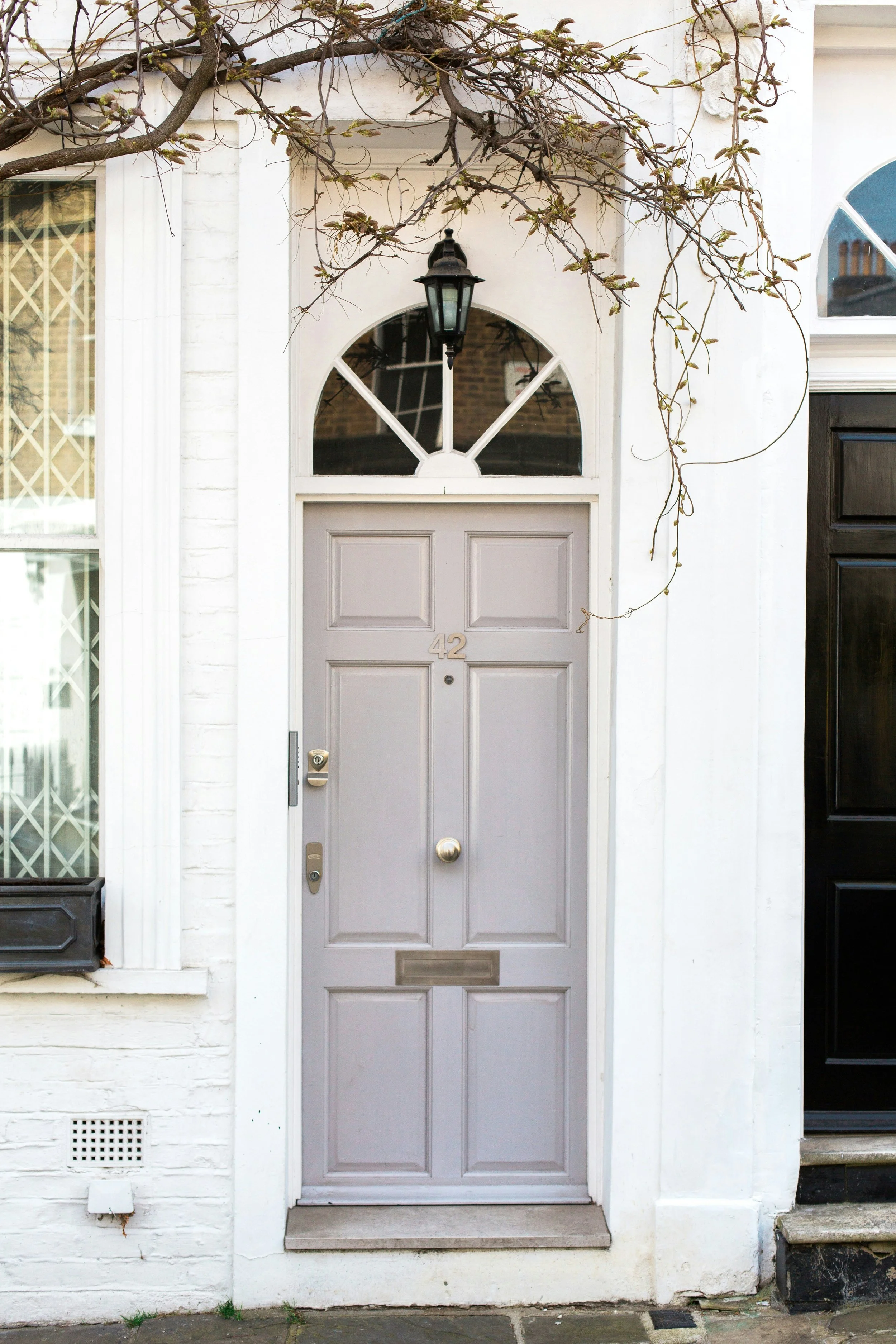 Light grey composite front door with fanlight glazing fitted to a traditional white-painted property in the West Midlands