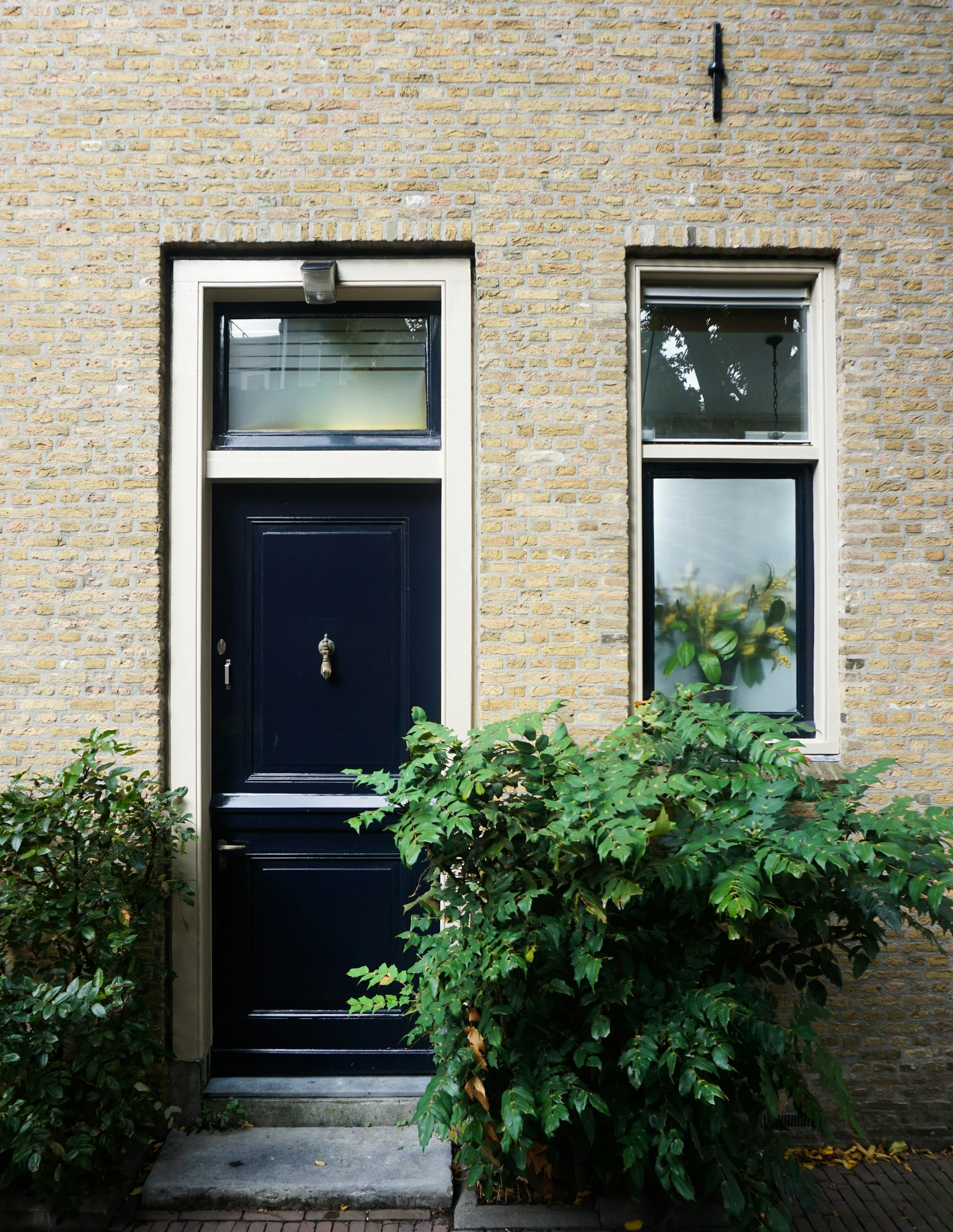 Dark blue traditional front door with matching window frame set within a light brick exterior at a West Midlands property