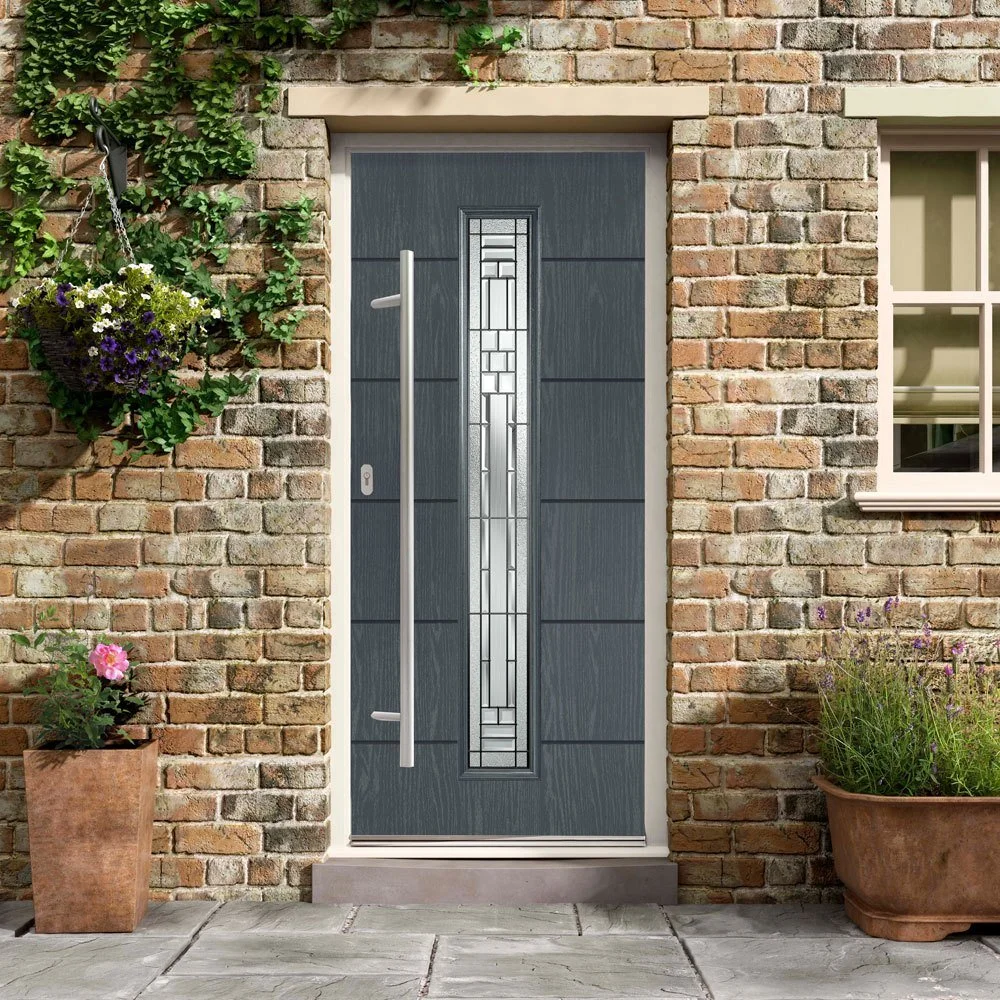 Grey composite front door with decorative glazed panel and long handle installed in brick property