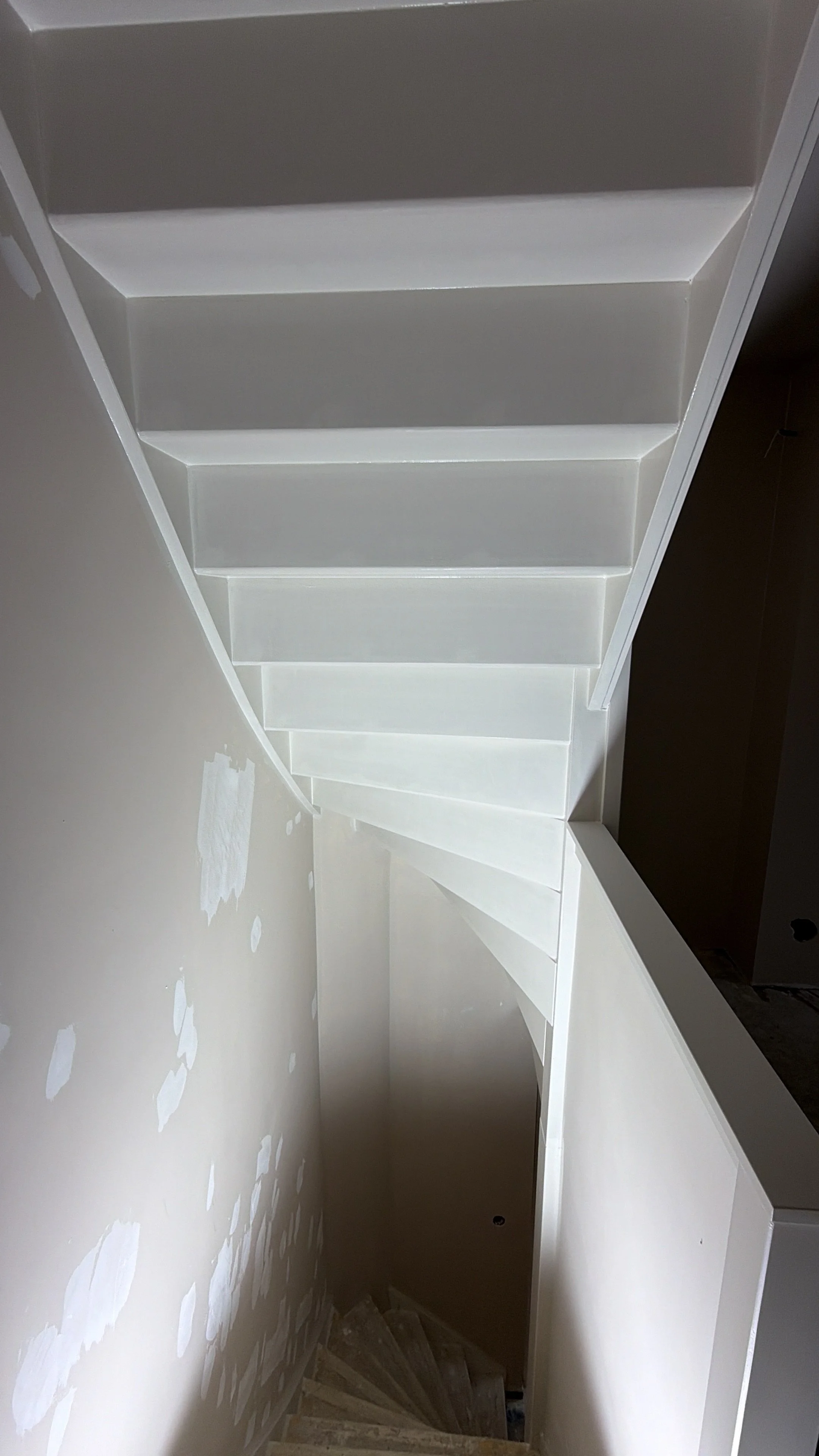 Binnende trap met witte treden en witte muren in een huis dat nog afgewerkt moet worden.