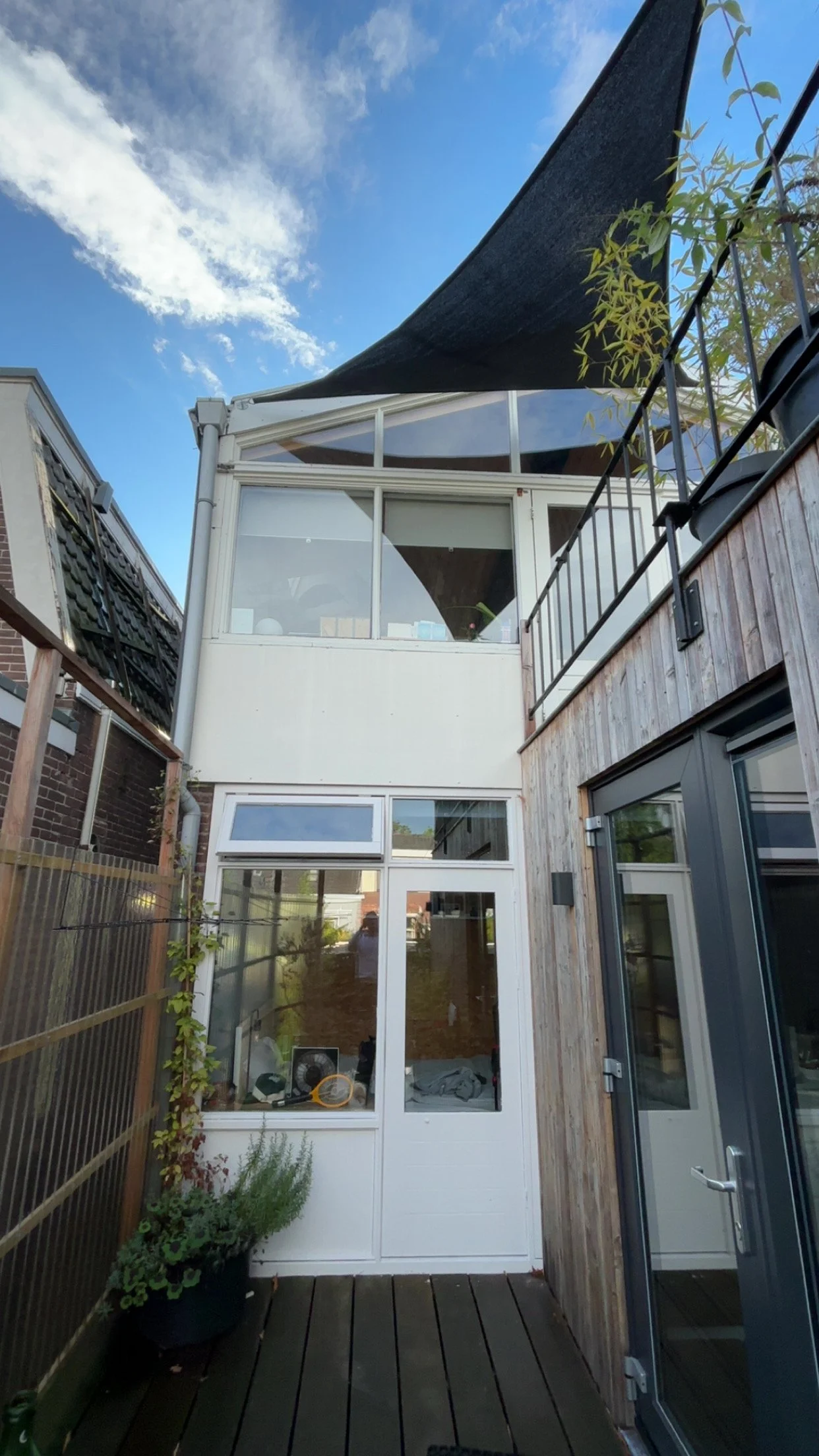 Kleine buitenruimte met houten vloeren, omgeven door houten en glazen gevels, met planten en een douchecabine.