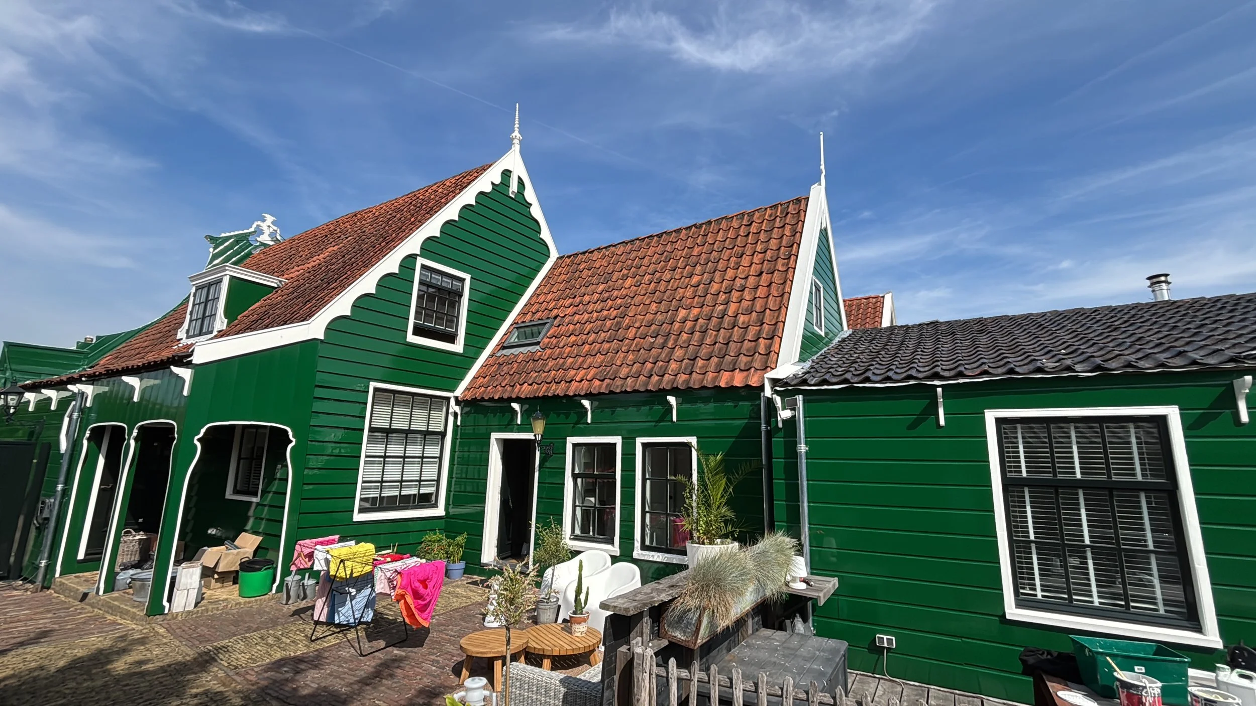 Groene huisjes met rood en zwart tegel daken en witte raamkozijnen onder een blauwe lucht.