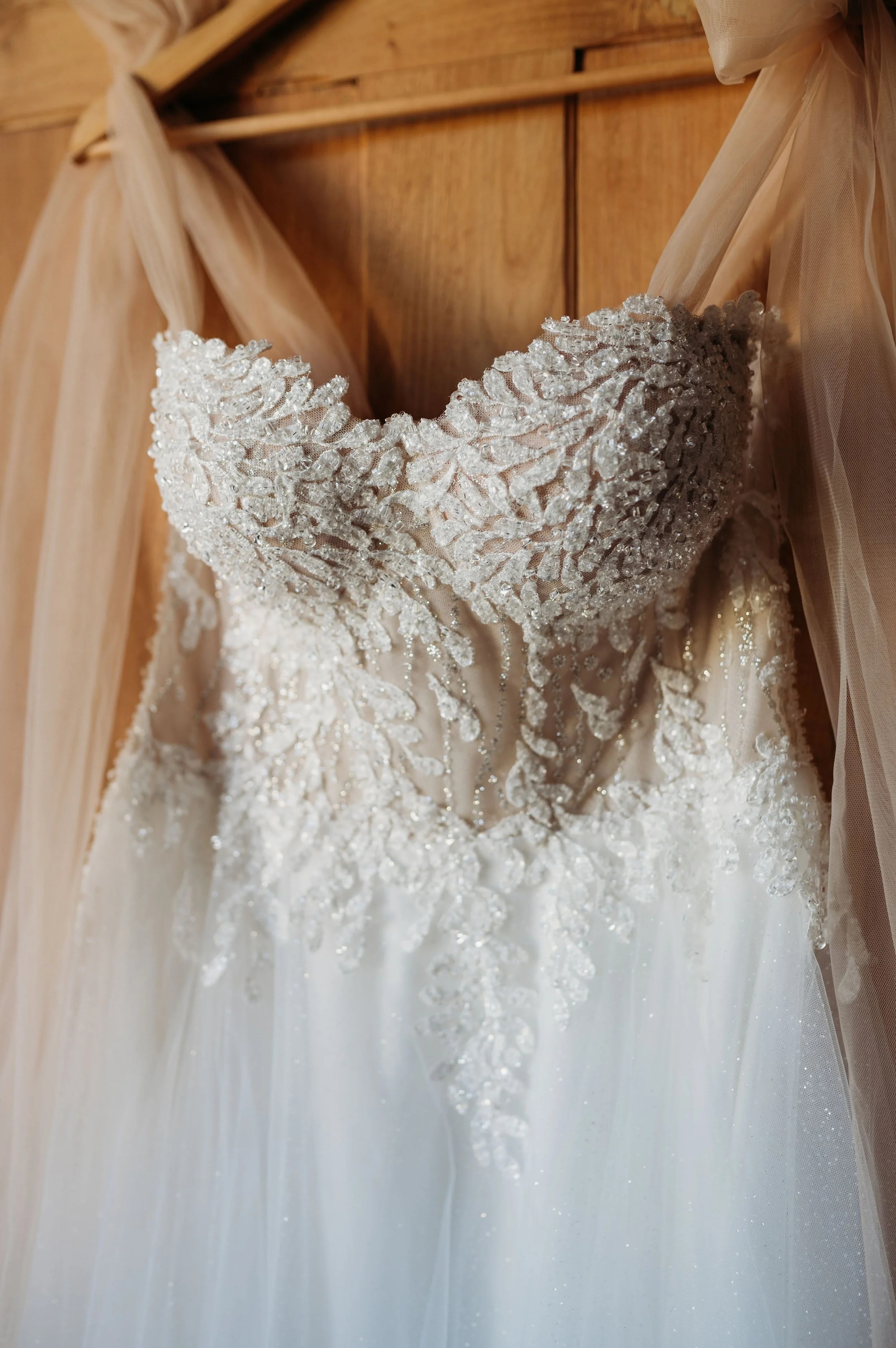 Detail na svatební šaty, dekorované perličkami a vyšívané květy.
