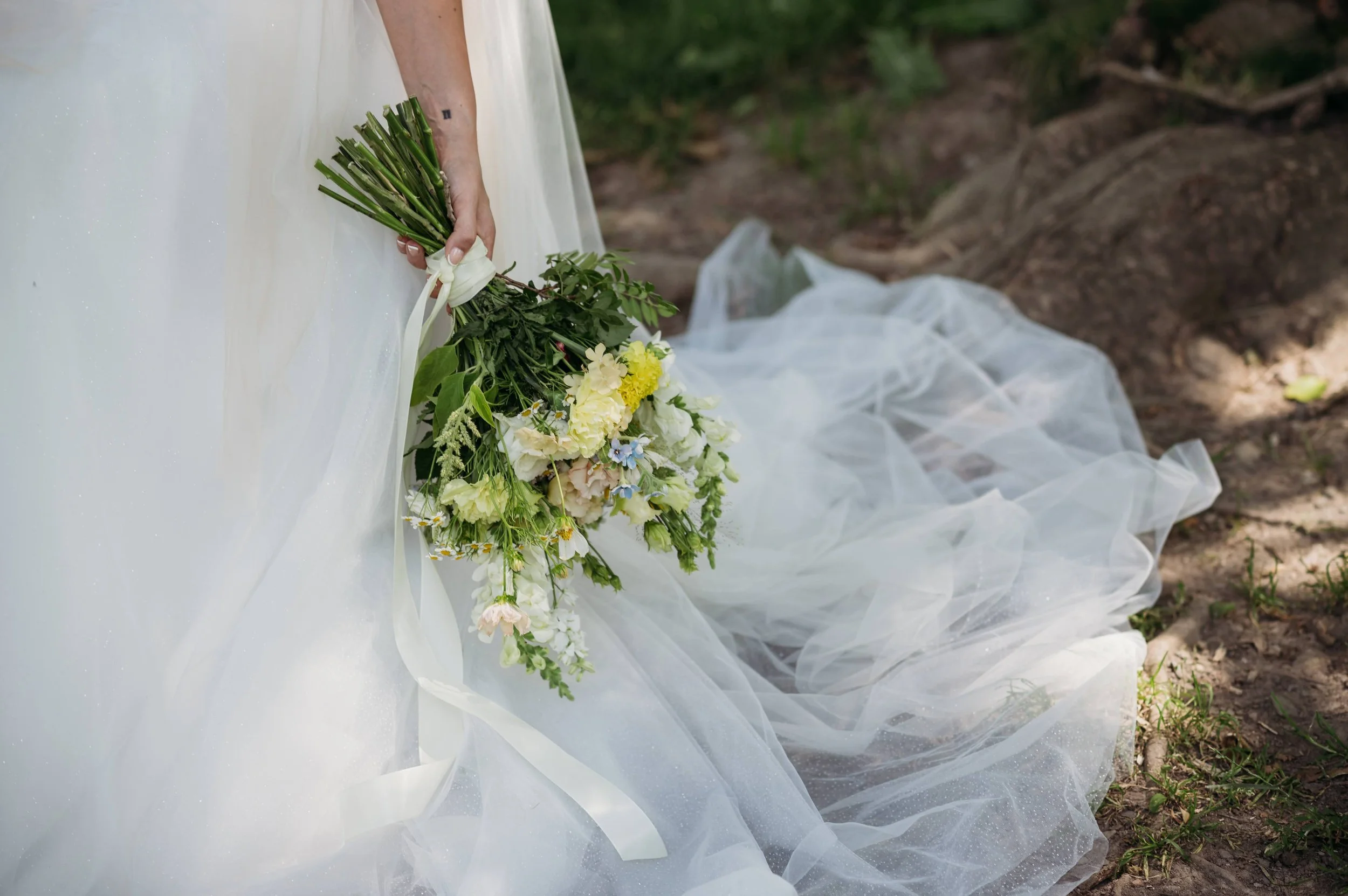 Laurie’s customers, Mariana and Carmen holding hands on a green lawn on their wedding day.