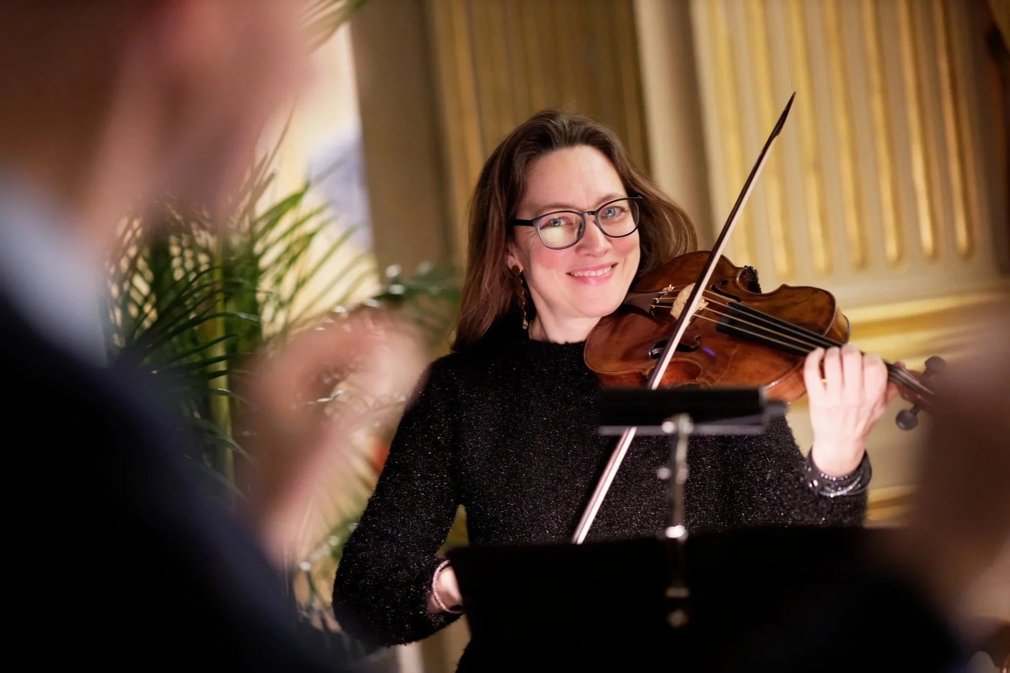 Violinist Laura Corolla, smiling while playing the violin at a music event.