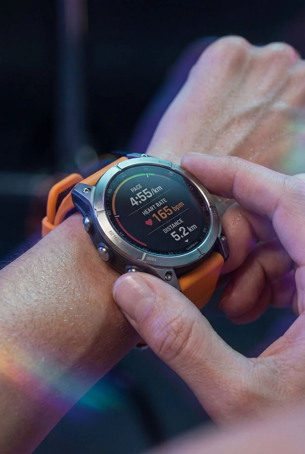 Close-up of a person wearing a smartwatch on their wrist during a workout, displaying pace, heart rate, and distance.