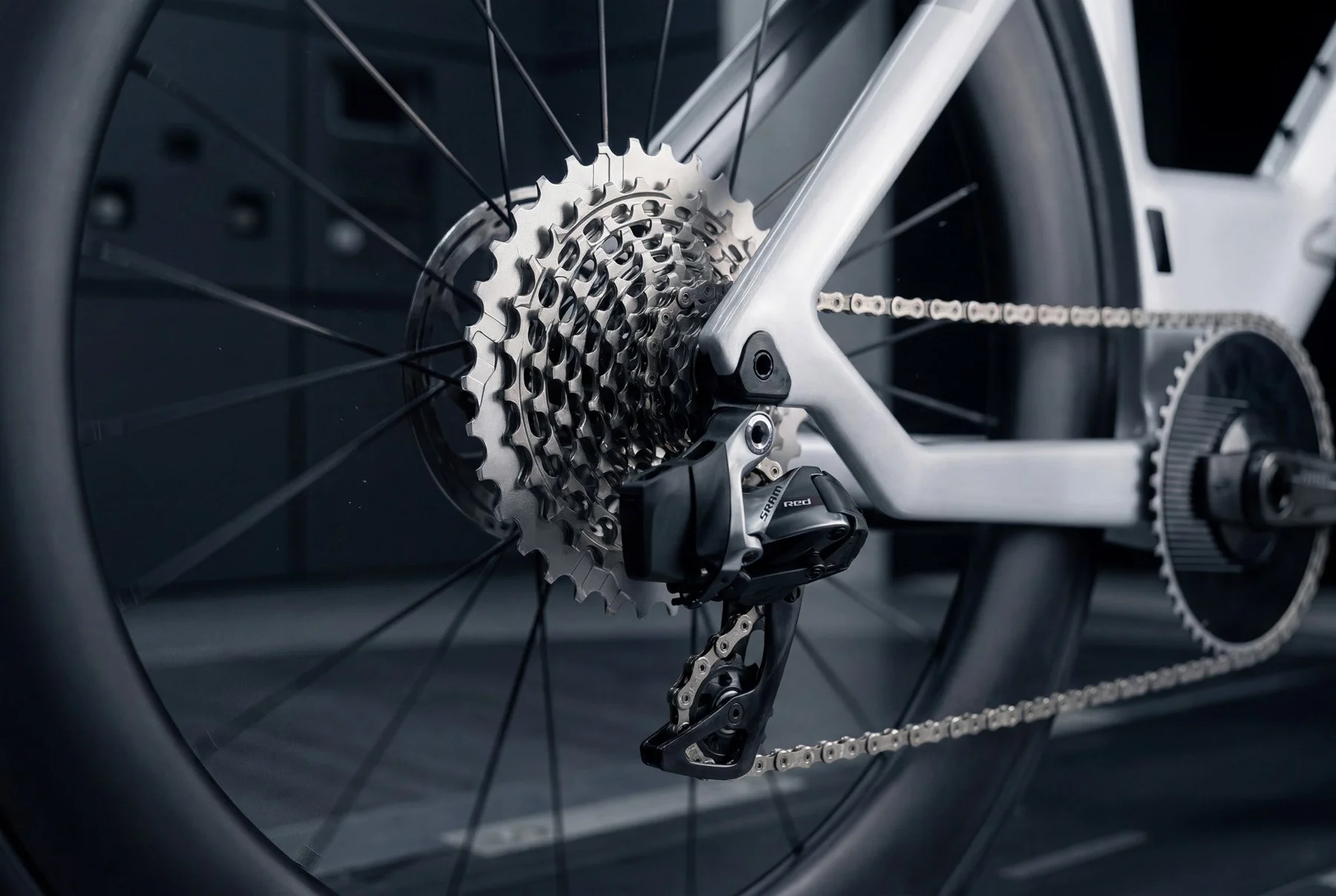 Close-up of a Canyon Speedmax CFR 1by AXS triathlon bicycle's rear wheel, showing the gears, chain, derailleur, and part of the frame.
