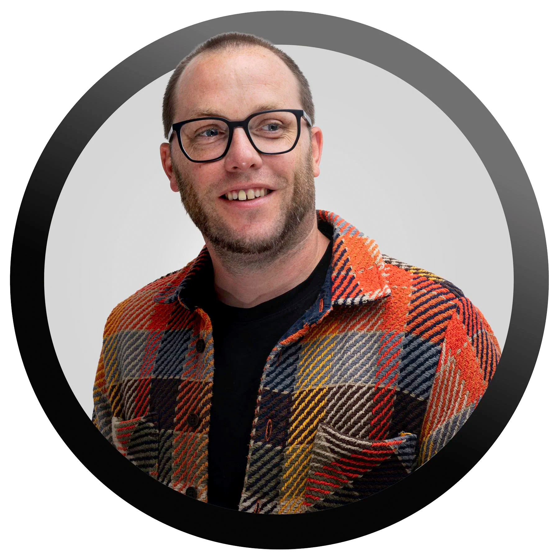 Smiling man with glasses, beard, and short hair, wearing a black shirt and a colorful plaid jacket, posing against a circular graphic background.