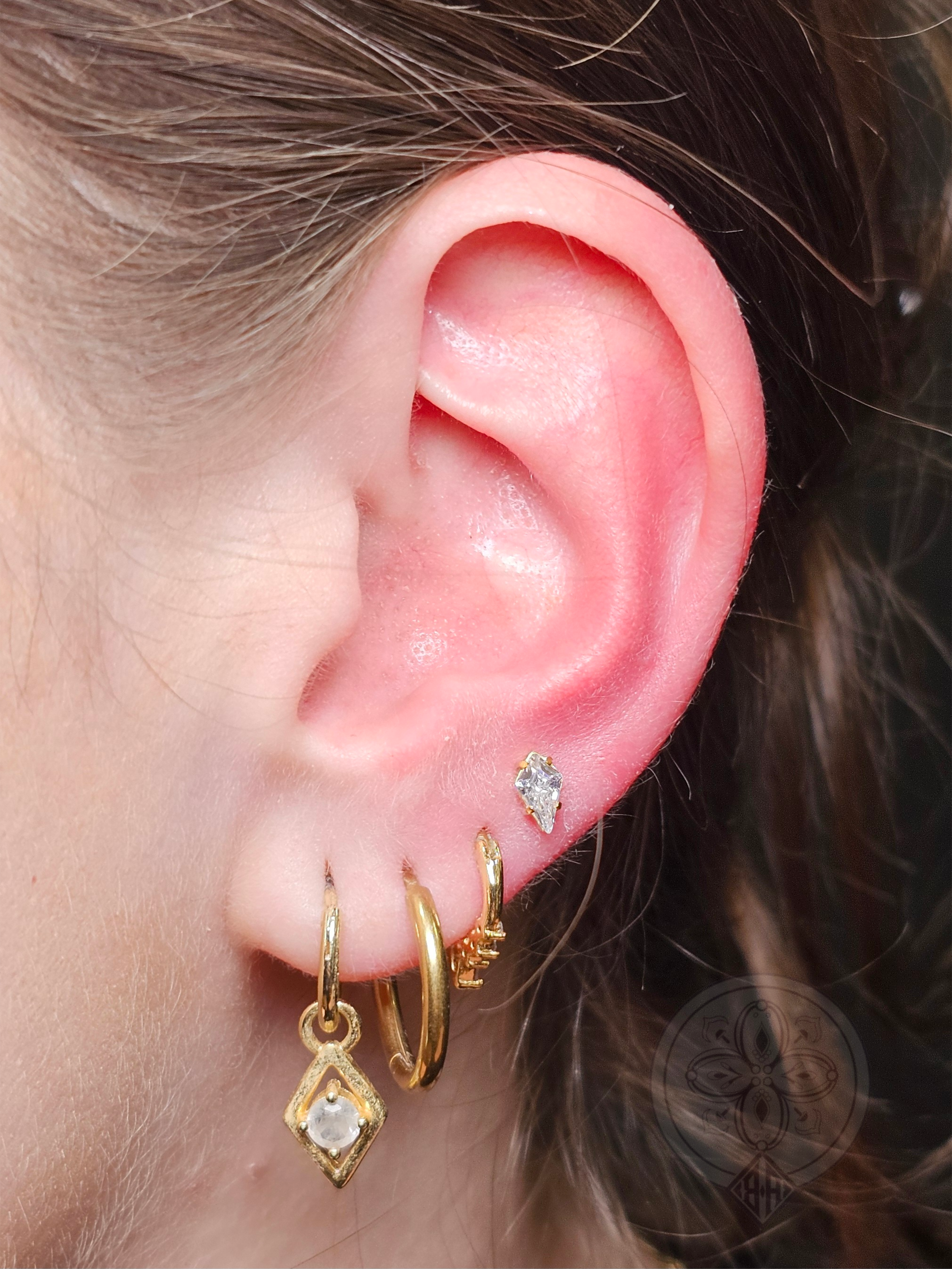 Ear curation with Gold jewellery . Ear lobe piercng