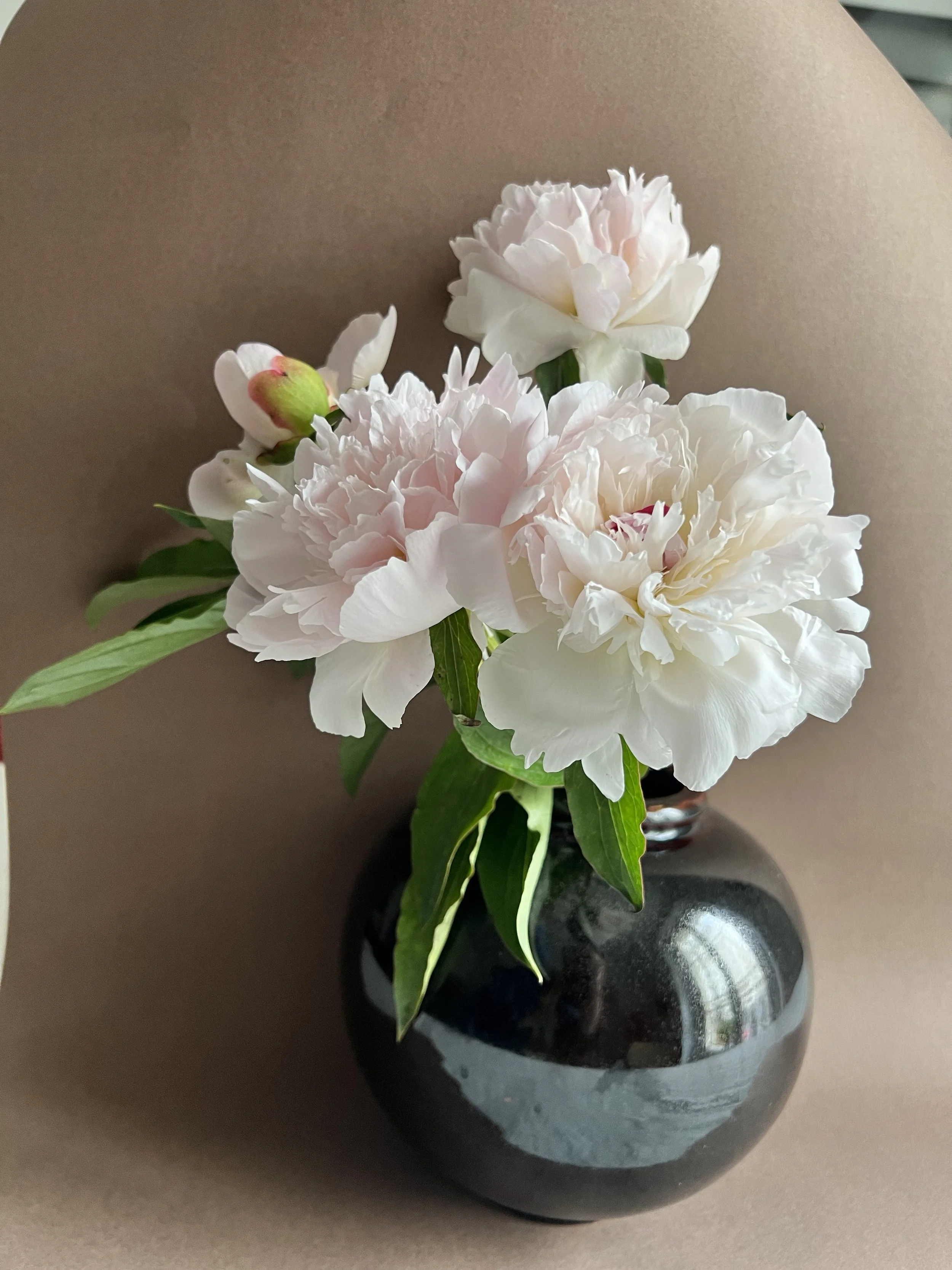 Bouquet de fleurs blanches et roses dans un vase en céramique marron aux reflets rouges