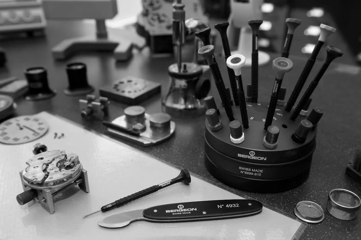 A watchmaking workshop with watch components, specialized tools, and watch parts on the table.