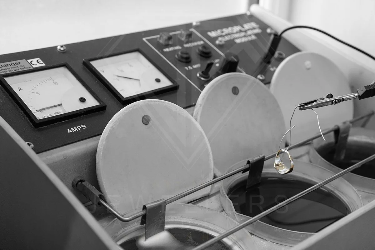 A laboratory setup with electrodes and a glass piece submerged in liquid, connected to electrical measuring instruments.
