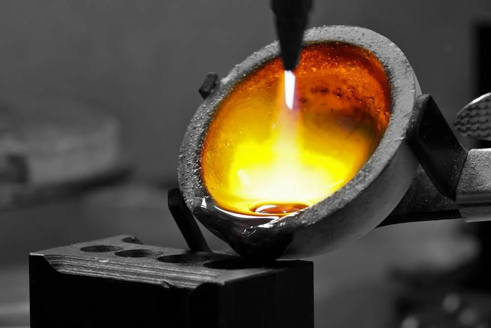 A smelting process where molten metal is being prepared in a fiery orange glow.
