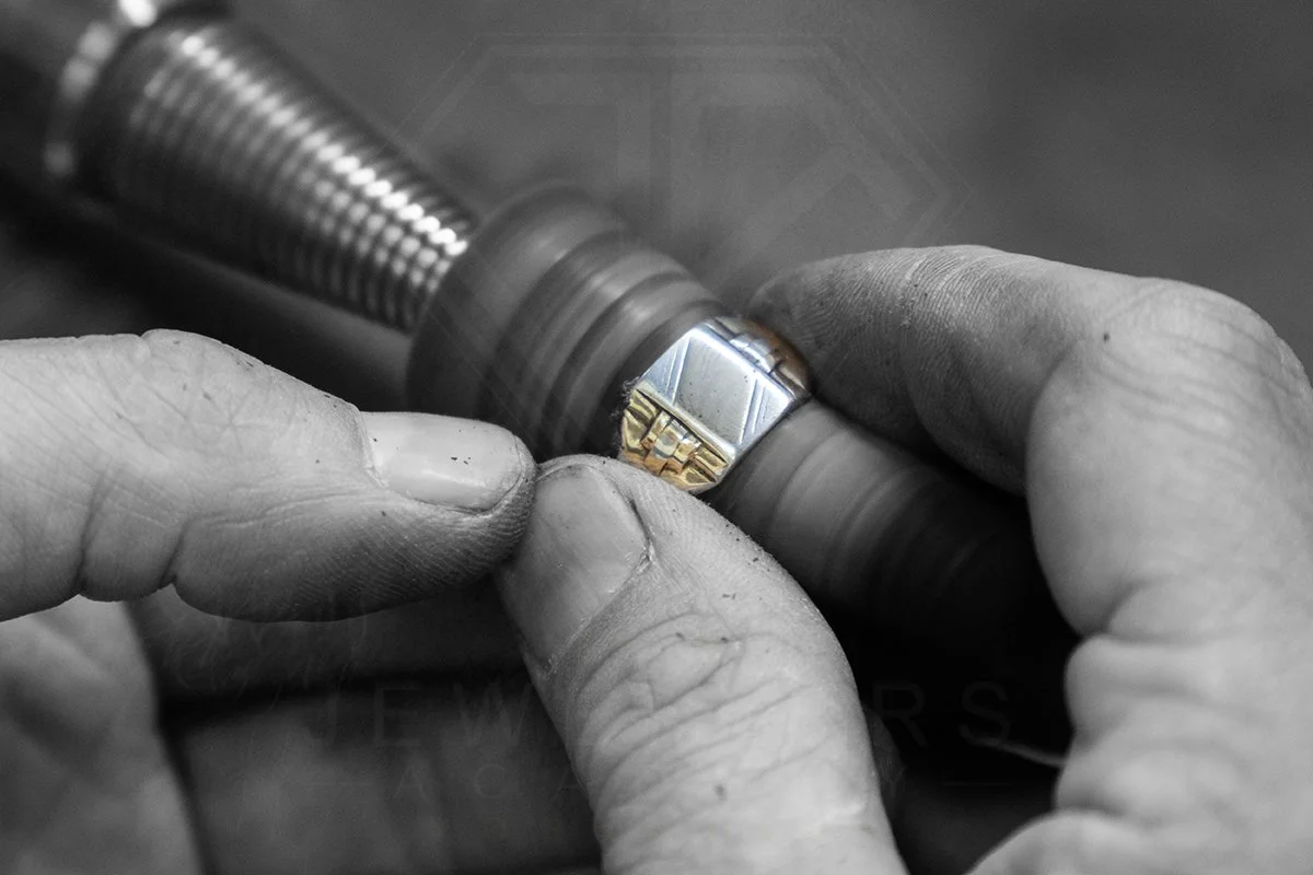 A person's hands working with a metal ring on a rotating lathe machine.