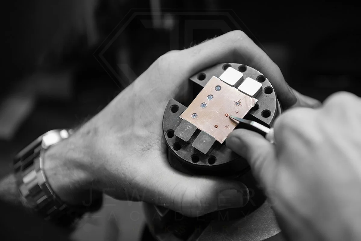 Close-up of hands assembling a small electronic component on a work holder in a workshop.
