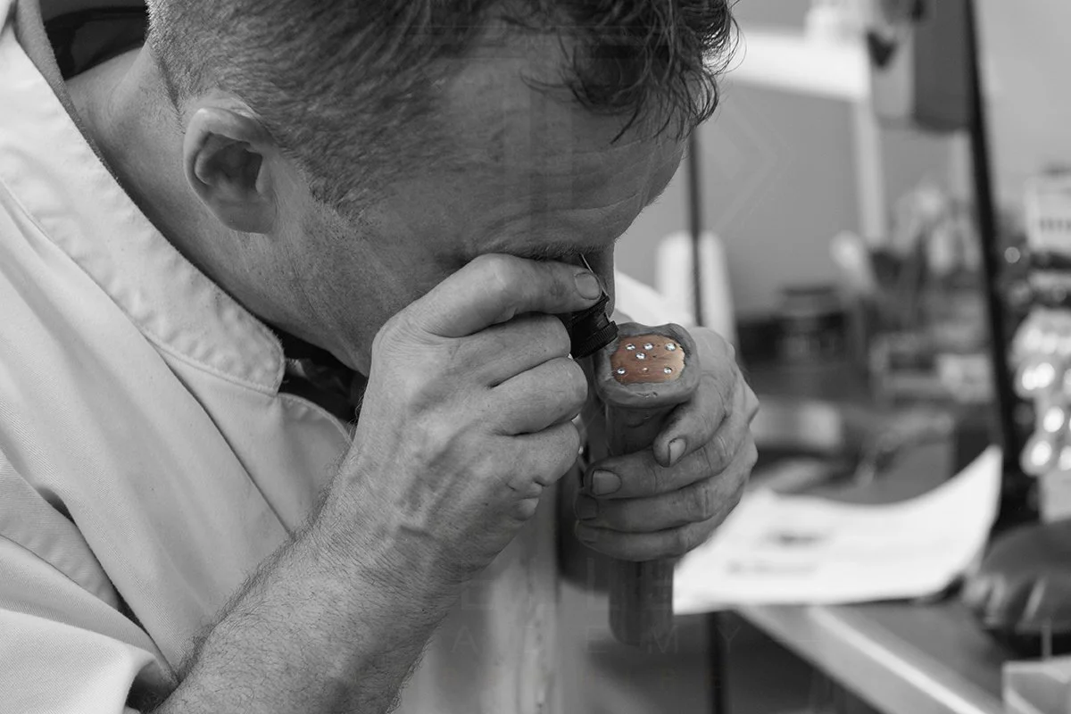 A man looking into a microscope, focusing intently on a dental model with teeth, in a clinical or laboratory setting.