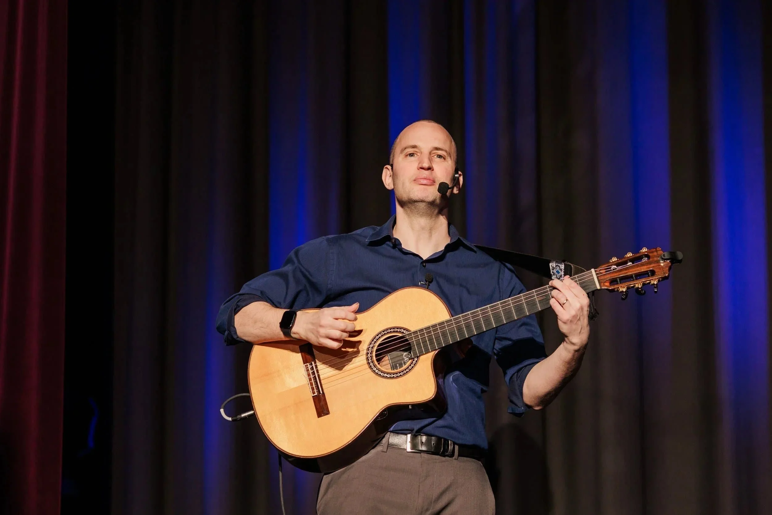 Jim Perona playing classical guitar in a performance setting