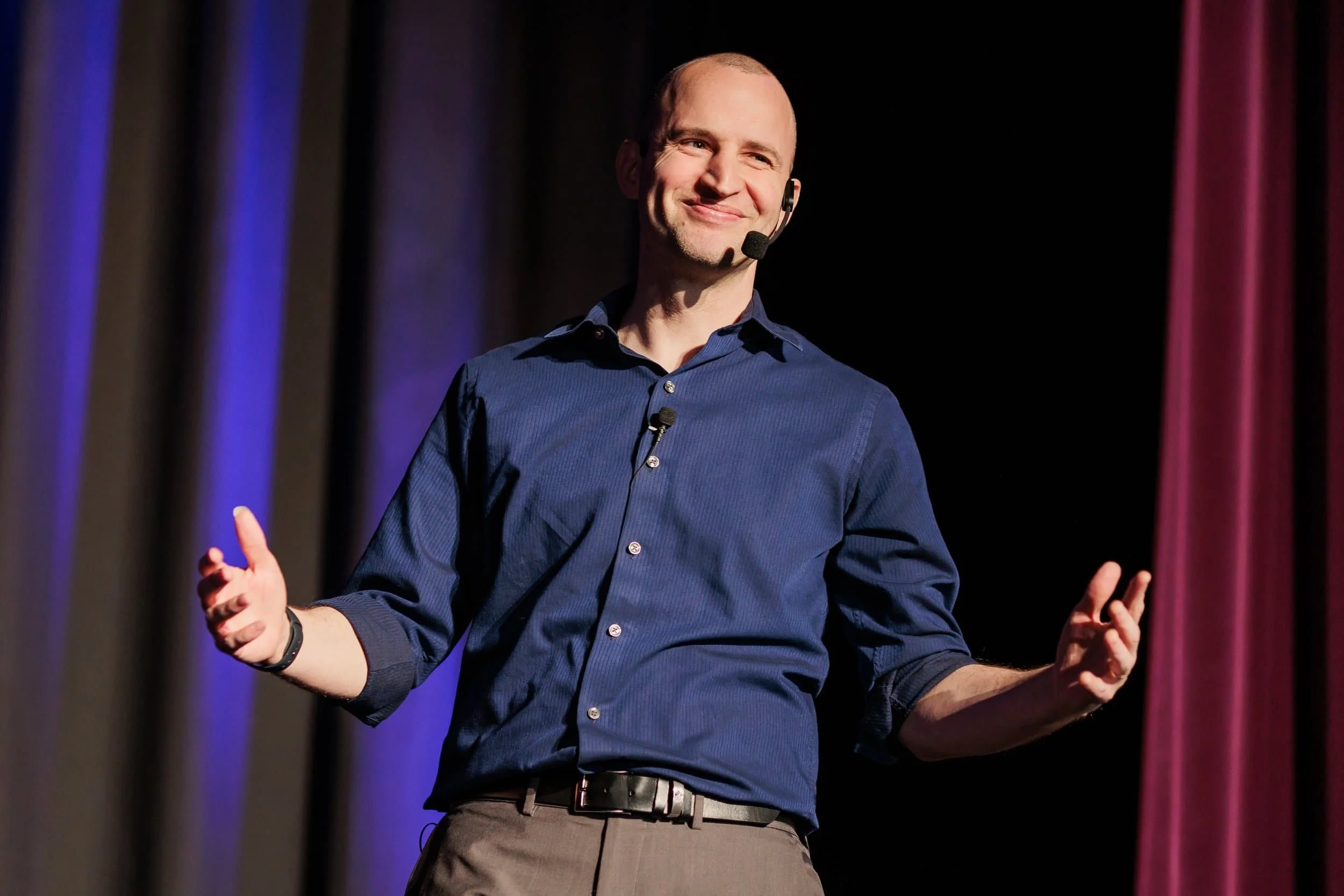 Jim Perona speaking and gesturing on stage at a keynote event