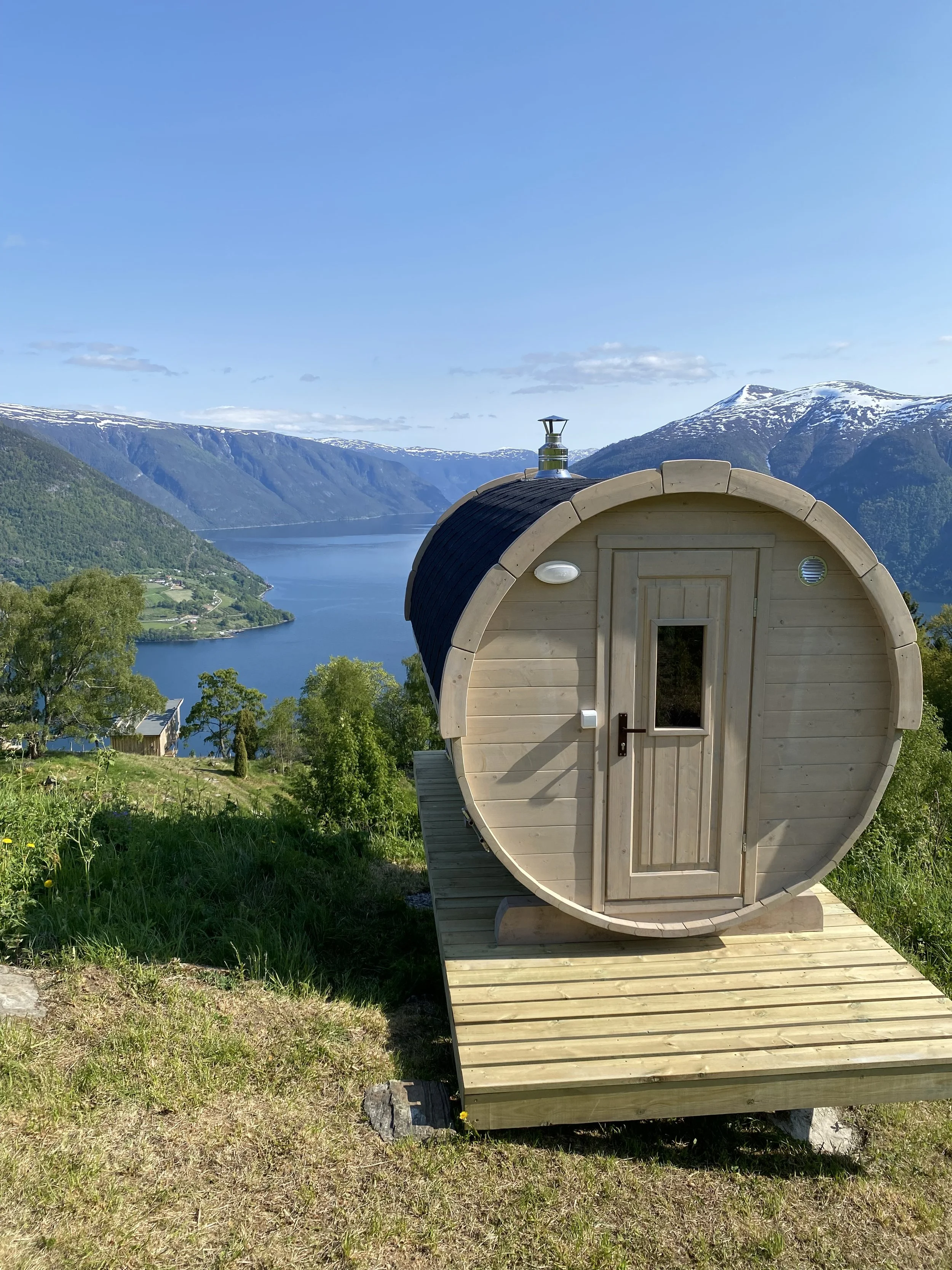 Liten rund badstue med utsikt over fjord og fjell i Norge.